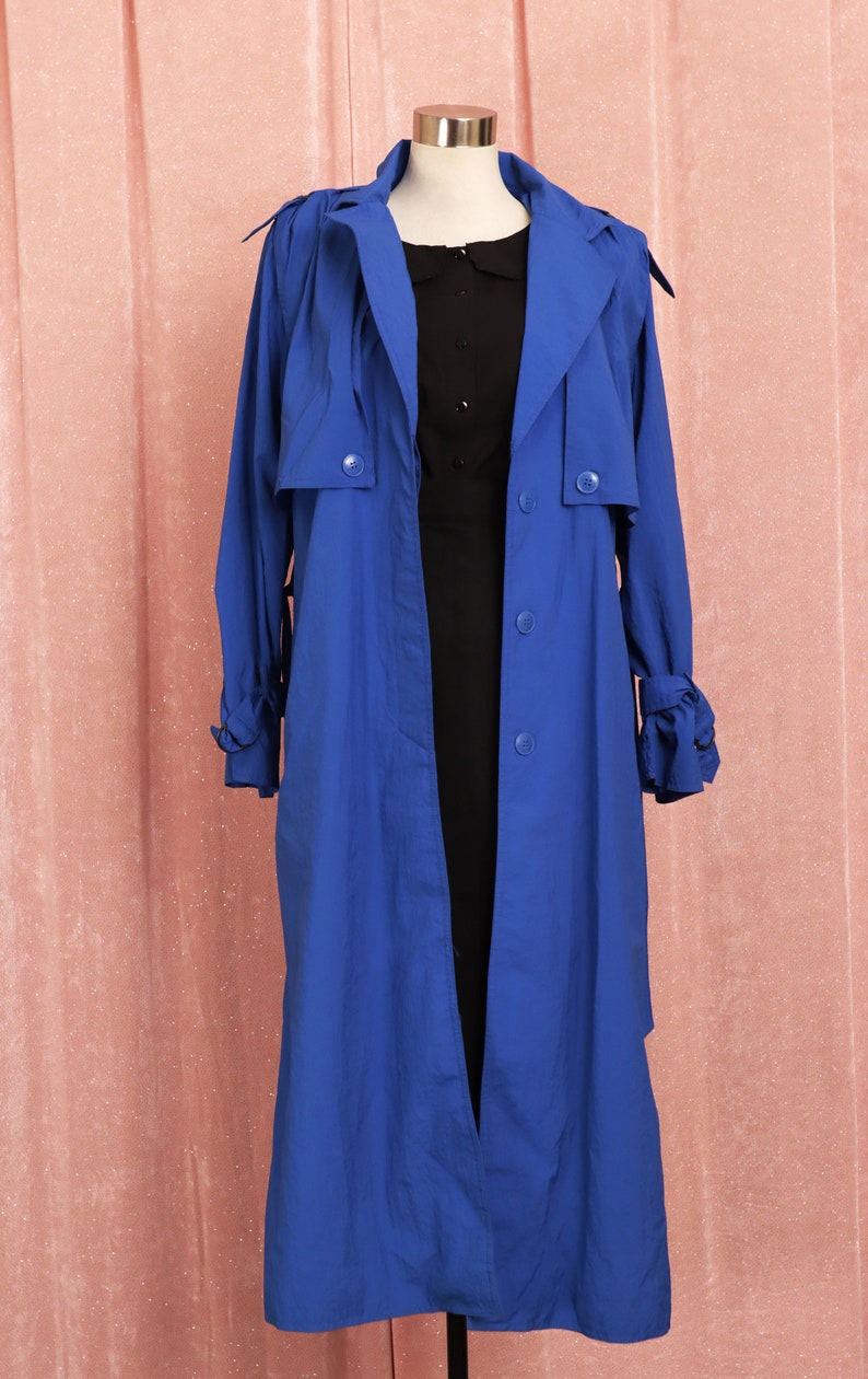 May include: A long, royal blue trench coat with a button closure and a tie at the cuffs.