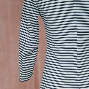 May include: A white and navy blue striped long-sleeved shirt. The shirt has a close-fitting, fitted style.