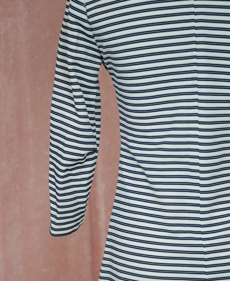 May include: A white and navy blue striped long-sleeved shirt. The shirt has a close-fitting, fitted style.