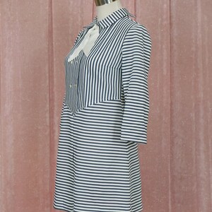 May include: A white and black striped dress with a white bow at the collar. The dress has a button-up front and long sleeves.