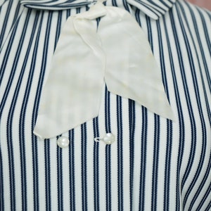 May include: A white and blue striped shirt with a white bow tie and pearl buttons.