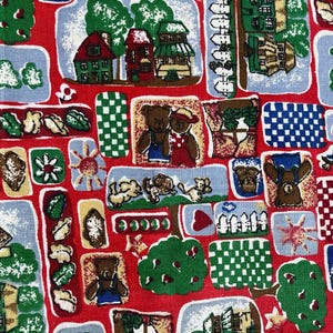 May include: Red fabric with a repeating pattern of houses, teddy bears, trees, and other whimsical elements. The design includes squares and rectangles with various patterns and illustrations, creating a playful and colorful aesthetic.