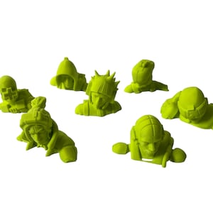 May include: Seven lime green figurines in various poses, each depicting a person with a helmet or head covering. The figures are lying down, with some raising their arms or giving a thumbs up. The background is plain white.