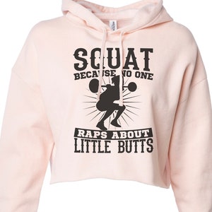 May include: Pink cropped hoodie with a black graphic that says "Squat because no one raps about little butts".