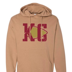 May include: A tan hoodie with a red and gold graphic of the letters "KC" with an arrowhead in the middle.
