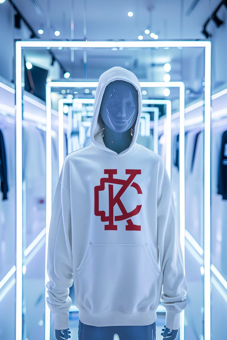 May include: White hooded sweatshirt with a red "KC" logo on the front. The sweatshirt is on a mannequin in a store setting.