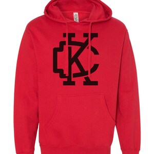 May include: Red hooded sweatshirt with a black "KC" logo on the front.