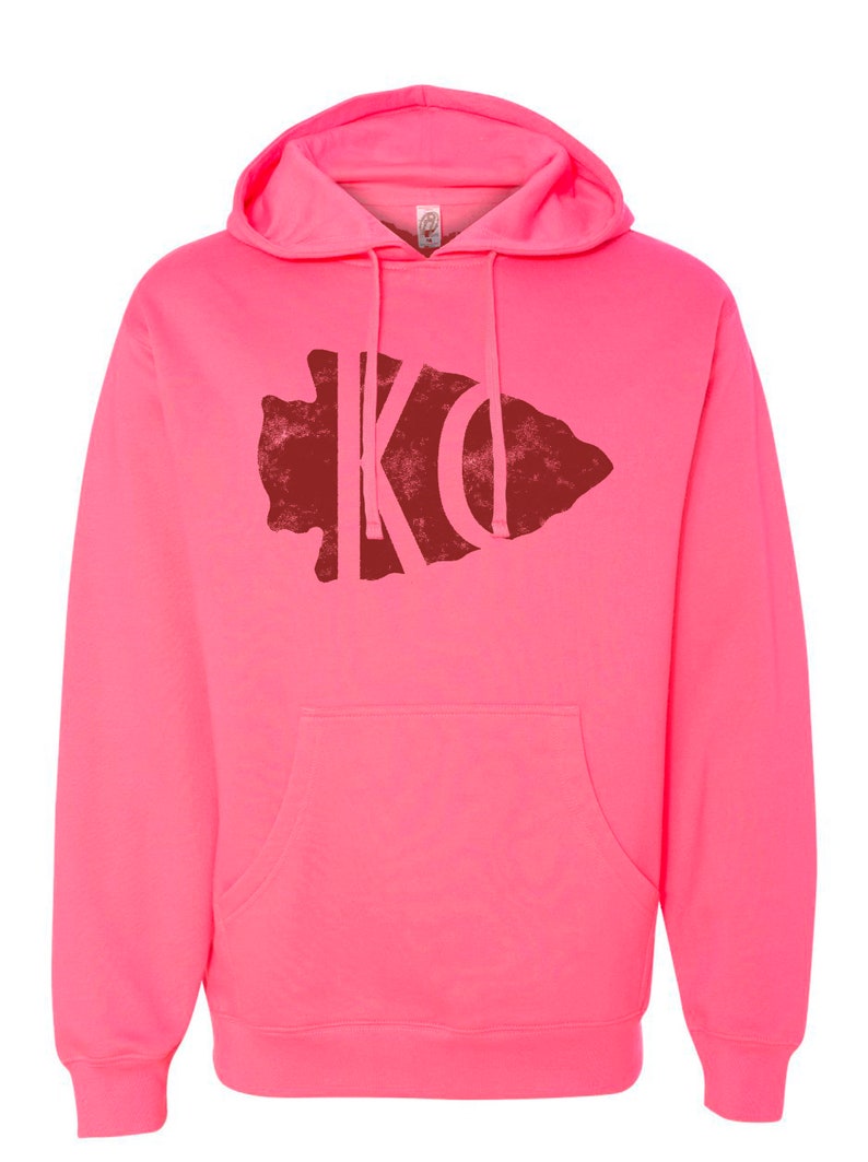 May include: A pink hooded sweatshirt with a red distressed arrowhead graphic featuring the letters "KO" inside.