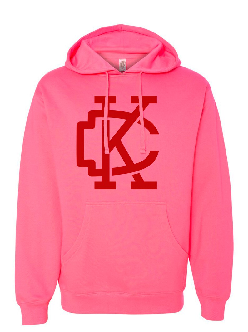 May include: A pink hoodie with a red "KC" logo on the front.
