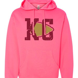 May include: A pink hoodie with a maroon "KC" graphic featuring a gold arrowhead.