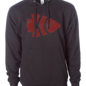 May include: Black hooded sweatshirt with a red distressed arrowhead graphic featuring the letters "KC" inside.