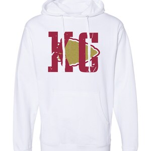 May include: White hooded sweatshirt with a red "KC" logo and a gold arrowhead graphic.