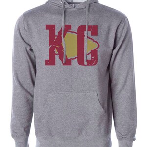 May include: A gray hooded sweatshirt with a red and yellow graphic of the letters "KC" with a stylized arrowhead in the middle.