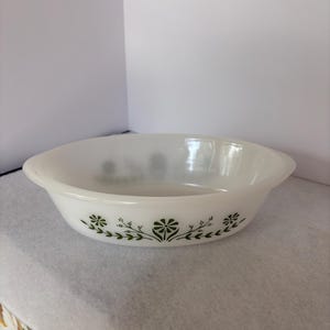May include: White oval Pyrex baking dish with green floral pattern. The dish has a simple design with a delicate green floral pattern around the rim. A classic piece for baking and serving.