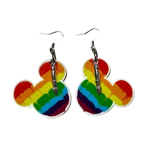 May include: A pair of rainbow paintbrush Mickey Mouse earrings. The earrings are made of acrylic and feature a rainbow paint splatter design with a silver paintbrush charm.