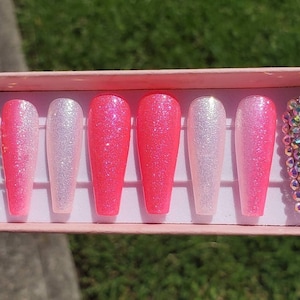 Peut inclure: Un ensemble de dix faux ongles longs, en d&eacute;grad&eacute; de rose et blanc avec des strass sur deux ongles.