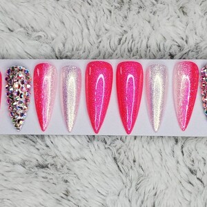 Peut inclure: Ensemble de dix faux ongles en pression avec d&eacute;grad&eacute; de rose et blanc, paillettes et strass.