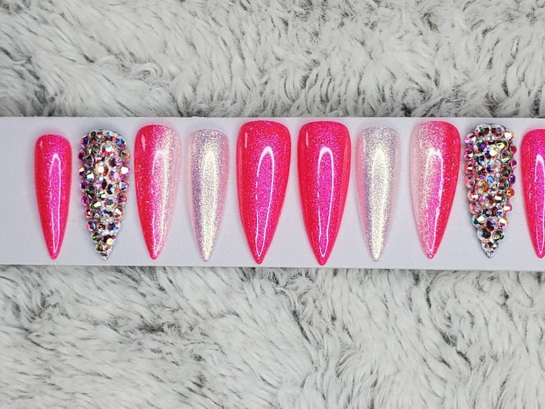 Peut inclure: Ensemble de dix faux ongles en pression avec d&eacute;grad&eacute; de rose et blanc, paillettes et strass.