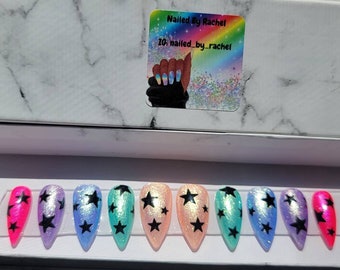 Puede incluir: Conjunto de diez uñas postizas iridiscentes con un diseño de estrella negra. Las uñas son de varios colores, incluyendo rosa, azul, verde y morado.