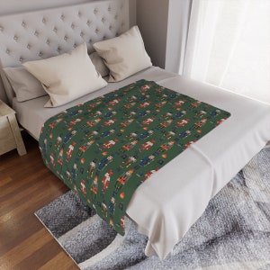 May include: A green throw blanket with a repeating pattern of nutcracker soldiers. The nutcrackers are wearing red, blue, and gold uniforms.