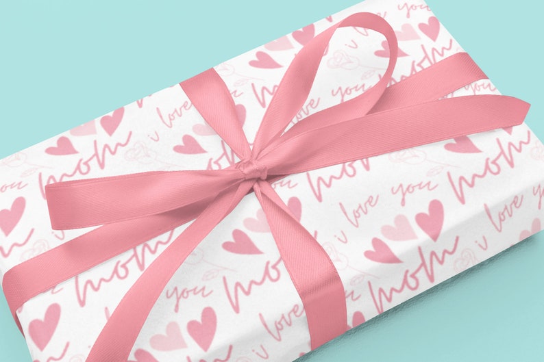 May include: A white gift box with a pink ribbon and a pink and white pattern of hearts and the words "mom" and "I love you".
