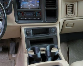 May include: The interior of a tan SUV with a black aftermarket radio and two black cup holders in the center console.