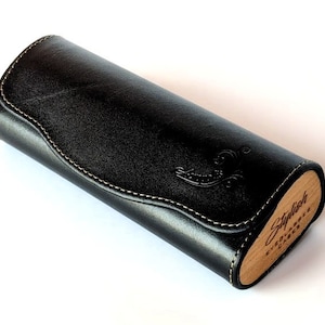 May include: Black leather glasses case with a wood end cap. The wood end cap has the text "Stylish Eyewear Cases" engraved on it.