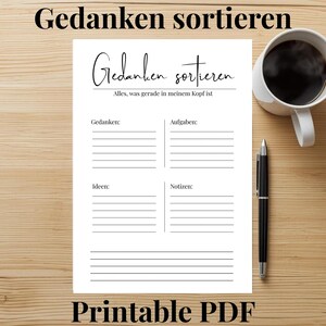 Könnte beinhalten: Eine weiße Keramik-Tasse mit schwarzem Henkel und dem Text "But First, Coffee" in fetter, schwarzer Schrift. Die Tasse steht vor einem neutralen Hintergrund, der ihr schlichtes Design hervorhebt.