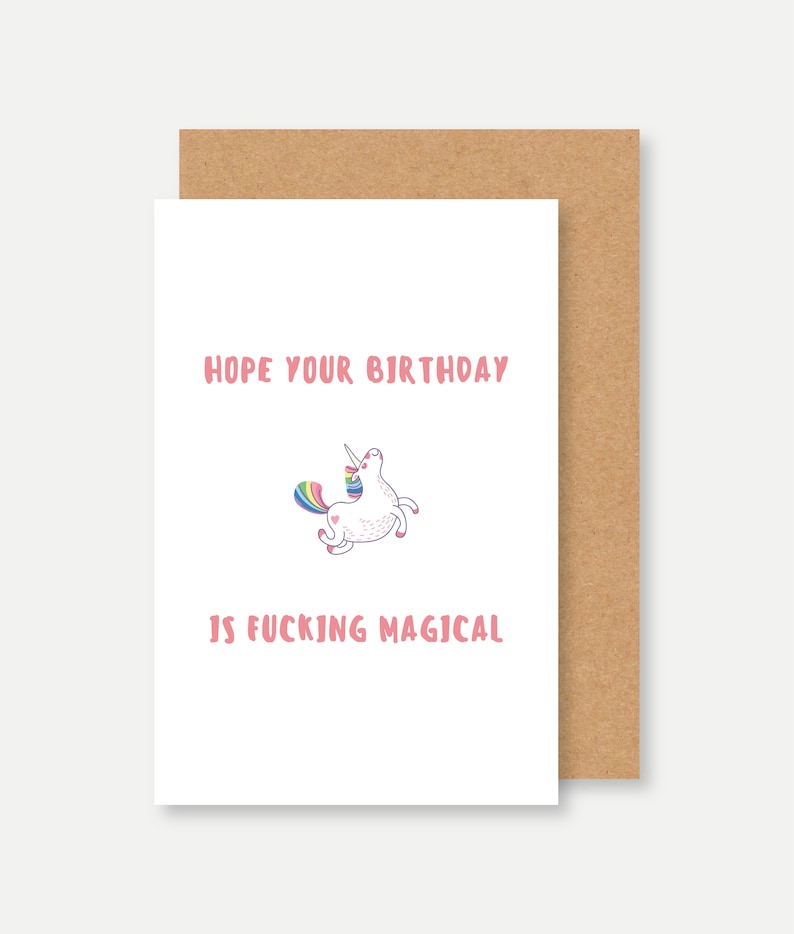 Puede incluir: Una tarjeta blanca con texto rosa que dice "Espero que tu cumplea&ntilde;os sea jodidamente m&aacute;gico." Un unicornio de dibujos animados con una melena y cola arco&iacute;ris est&aacute; en el centro de la tarjeta.
