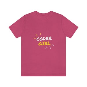 May include: A magenta t-shirt featuring the text "CODER GIRL" in white and yellow, with yellow and white accents. The shirt has a crew neck and short sleeves.