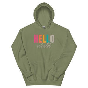 Puede incluir: Una sudadera con capucha verde oliva con un bolsillo delantero. La palabra "HELLO" está impresa en rosa, naranja y turquesa, con una "O" gris. La palabra "world" está impresa debajo en una fuente cursiva.
