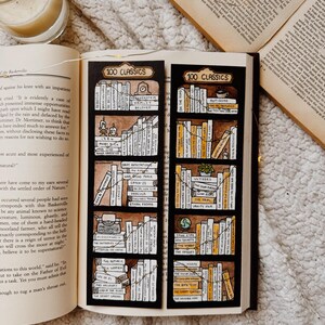 May include: Two black bookmarks, each labelled "100 Classics", display hand-drawn bookshelves filled with classic literature. The bookmarks are placed on an open book, with a lit candle and fairy lights.