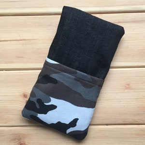 Pode incluir: Uma capa de telefone de brim preto com forro de tecido camuflado. A capa est&aacute; dobrada ao meio e est&aacute; sobre uma superf&iacute;cie de madeira.