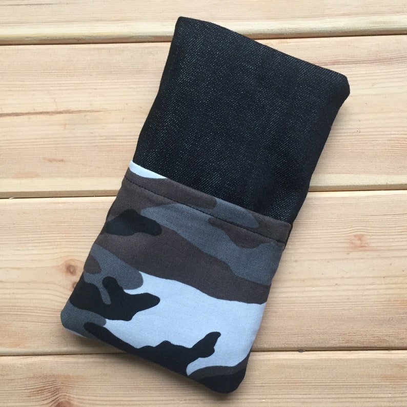 Pode incluir: Uma capa de telefone de brim preto com forro de tecido camuflado. A capa est&aacute; dobrada ao meio e est&aacute; sobre uma superf&iacute;cie de madeira.