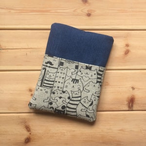 Puede incluir: Una bolsa con cremallera de denim y lino con un estampado de gatos blanco y negro. La bolsa tiene una solapa de denim azul con cierre de cremallera.