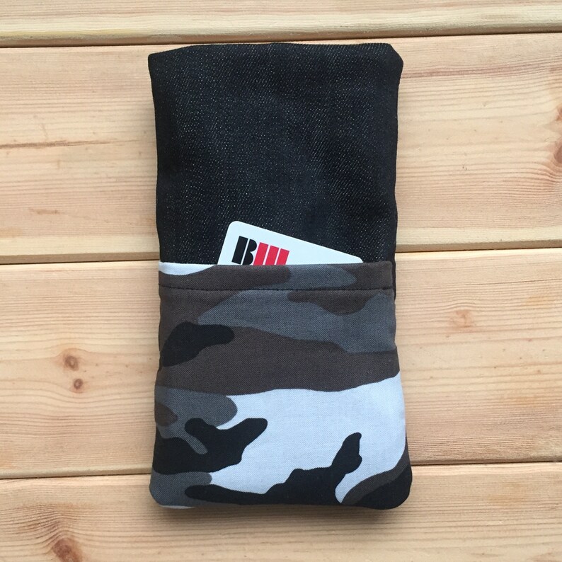 Pode incluir: Uma bolsa de ganga preta com forro de tecido de camuflagem. A bolsa tem um pequeno bolso na frente com um cart&atilde;o branco que diz "BUL" em letras pretas e vermelhas.