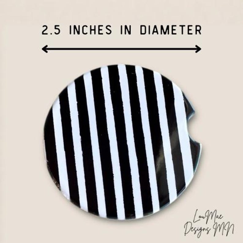 May include: A round car coaster with a black and white striped pattern. The coaster is 2.5 inches in diameter. The design includes a small cutout for easy removal from a car cup holder.