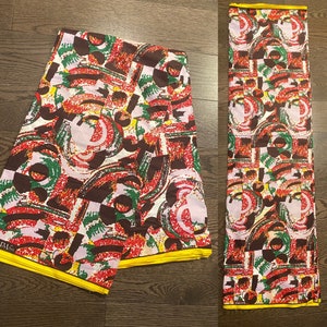Peut inclure: Deux morceaux de tissu coloré avec un motif géométrique dans des tons de rouge, vert, marron, blanc et jaune. Le tissu a une bordure jaune.