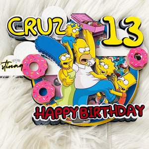 May include: A yellow, blue, and pink cake topper featuring the Simpsons family. The topper says "Cruz 13 Happy Birthday".