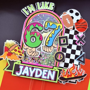 May include: A colorful birthday cake topper with the text "I'M LIKE" above the numbers "67". The topper includes a name, sports balls, and a skateboard with flames. The design features a pizza slice and french fries.