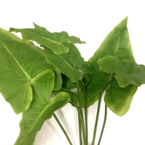 May include: A cluster of artificial green leaves with prominent veining. The leaves are a vibrant green color and have a smooth texture. The stems are a dark green color. The leaves are arranged in a natural, organic way.