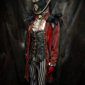 May include: A costume featuring a red long coat with black feather epaulets, a dark corset with metal buckles, and black and white striped leggings. The ensemble includes a top hat with a checkered pattern, a skull accent, and a ruffled white shirt.