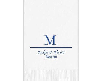 May include: White paper napkin with a blue "M" monogram and the text "Jaclyn & Victor Martin" in blue script.