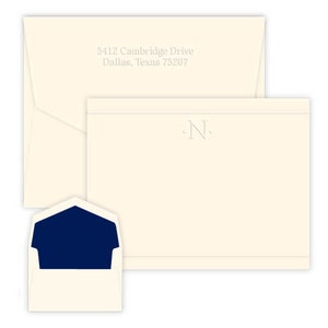 May include: A set of ivory stationery with a navy blue envelope liner. The stationery features a single initial "N" in a simple, elegant font. The envelope is addressed to 5412 Cambridge Drive, Dallas, Texas 75207.
