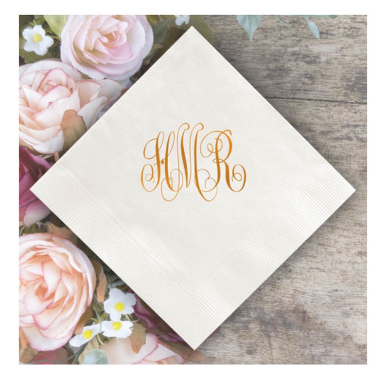 May include: White linen napkin with a gold monogram of the letters "HVR" in a script font.