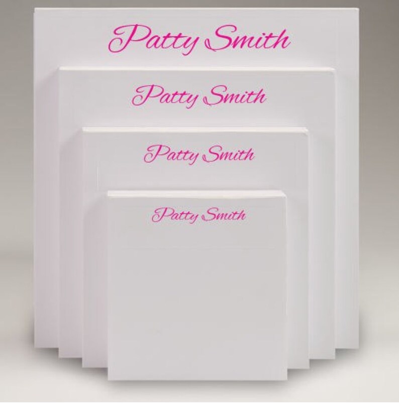 Pu&ograve; includere: Quattro blocchi di note bianchi impilati uno sopra l'altro. Ogni blocco di note ha il nome "Patty Smith" stampato in corsivo rosa.