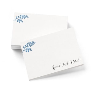 May include: A stack of white notecards with a blue leaf design in the upper left corner. The bottom card has the text "Your Text Here!" in black script. The cards are on a white background.