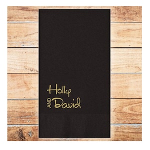 May include: Black wedding napkin with gold lettering that reads "AND Holly David"