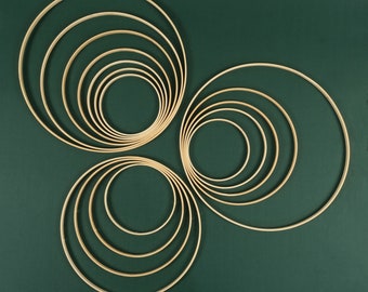 Puede incluir: Un conjunto de aros de madera concéntricos, dispuestos en un patrón circular sobre un fondo verde. Los aros están hechos de madera natural y tienen un acabado liso y pulido.