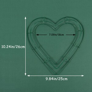 K&ouml;nnte beinhalten: Gr&uuml;ner, herzf&ouml;rmiger Kranzrahmen aus Metall mit zwei Schichten. Der Rahmen misst 10,24 Zoll mal 9,84 Zoll, oder 26 cm mal 25 cm.